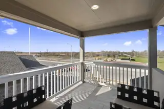 A spacious balcony with sleek railings overlooking a serene neighborhood and park.