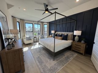 A luxurious owner’s suite with a dramatic accent wall, four-poster bed, and expansive windows flooding the space with natural light.