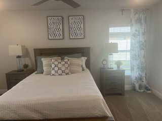 Cozy bedroom with a wooden bed, patterned cushions, modern lamps, and floral curtains.