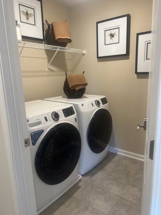 A cozy laundry room featuring sleek appliances, neutral walls, and stylish insect-themed artwork for added charm.