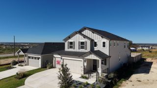 A modern two-story home with a spacious driveway and manicured landscaping in Seasons at Calumet II by Richmond American Homes (Jarrell, TX).