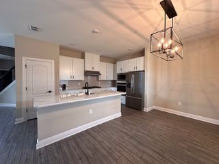 A modern kitchen with sleek white cabinets, stainless steel appliances, and an elegant pendant light.