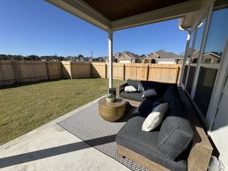 A cozy patio with a sectional sofa, a round coffee table, and a fenced backyard.