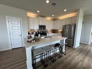 A modern kitchen with white cabinets, stainless appliances, a large island, and stylish lighting.