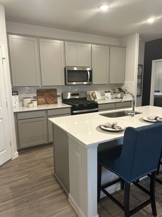Model Home A modern kitchen with sleek cabinetry, stainless steel appliances, and a pristine island featuring stylish seating.