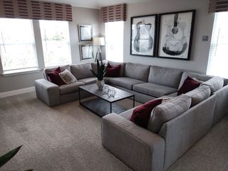 A cozy living room featuring a gray sectional sofa, patterned cushions, and artistic guitar wall decor.