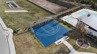 Community Amenities An aerial view of the Crescent Bluff sports court by Scott Homes (Georgetown, TX), featuring a blue basketball court, pool, and surrounding green spaces.