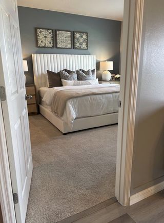 A cozy bedroom featuring a plush upholstered bed, elegant gray walls, and chic decorative accents.