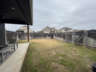 A spacious backyard with a covered patio and wooden fencing, perfect for outdoor activities.