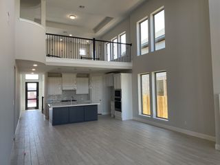 An elegant open-concept space with high ceilings, large windows, and a sleek kitchen island.