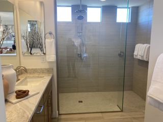 A modern bathroom with a glass-enclosed shower, dual vanities with granite counters, and neutral tile flooring offers a clean and elegant design.