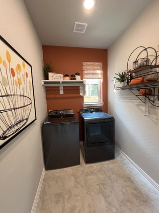 A stylish laundry room with bold accent walls, sleek appliances, and organized shelving in Solterra by Chesmar Homes (Mesquite, TX).