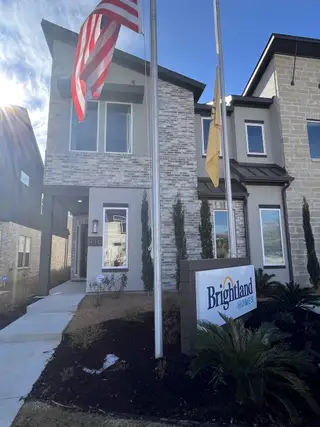 Street view The elegant exterior of a home with bright flags and landscaping in Collin Creek by Brightland Homes (Plano, TX).