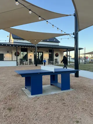 A shaded outdoor ping-pong table near the clubhouse, perfect for community fun in Harvest Ridge by Brohn Homes (Elgin, TX).