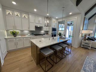 A bright and airy kitchen with white cabinetry, gold hardware, and a large quartz island, blending modern and classic elegance.