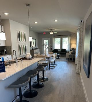 A modern open-concept kitchen and living area with sleek counters, stylish barstools, and abundant natural light.