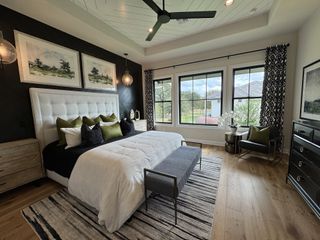 Model Home A luxurious bedroom with a tufted headboard, elegant decor, and scenic views through large windows.