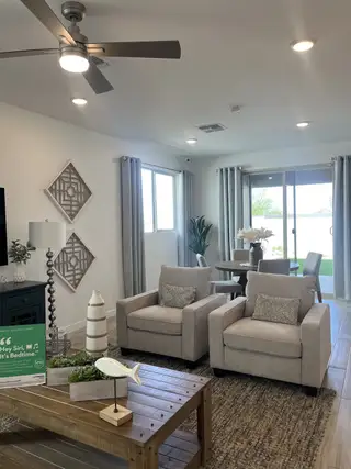 A cozy living area with plush armchairs, a wooden coffee table, and modern accents, leading to a dining space and patio.