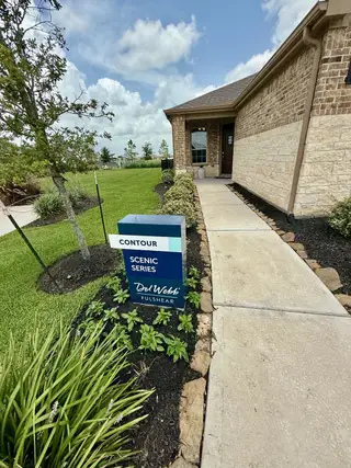 Street view A charming brick home with a landscaped yard in Del Webb Fulshear by Del Webb (Fulshear, TX).