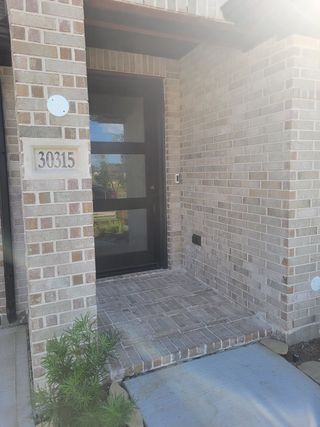 A charming brick entryway with modern glass door in Fulbrook on Fulshear Creek 60' by Perry Homes (Fulshear, TX).