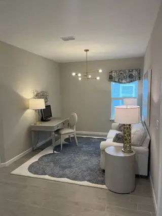 A cozy home office with modern lighting, a chic desk, and a plush area rug, creating an inviting atmosphere.