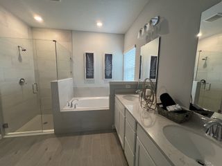 A modern bathroom with a glass-enclosed shower, dual sinks, and elegant decor accents on the counters.