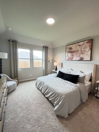 Model Home A cozy bedroom with a plush bed, abstract artwork, and large windows framed by elegant curtains.