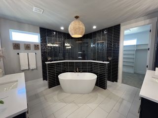 A luxurious bathroom with a freestanding tub, black-tiled accent wall, and modern vanity, offering a sleek, contemporary design.