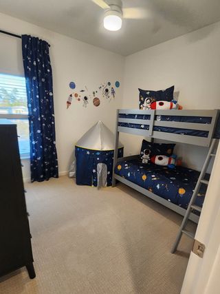 A playful children's room with space-themed decor, bunk beds, and a cozy reading tent.