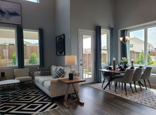 Model Home A modern living-dining area with high ceilings, natural light, and chic decor.