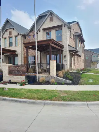 A stunning brick and stone home with a wooden pergola in The Tribute by Grenadier Homes, The Colony, TX.