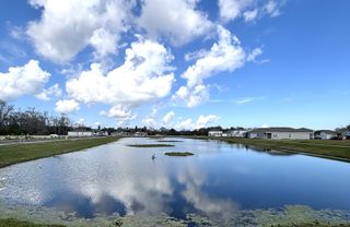 A picturesque lake reflecting the sky and surrounding homes, creating a tranquil and inviting atmosphere in the community.