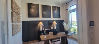 Model Home A stylish home office featuring modern decor, large windows, and elegant art pieces above a sleek desk.