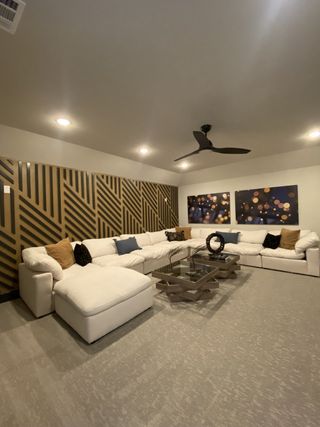 A contemporary living room with a large white sectional sofa, modern decor, and geometric wall design.