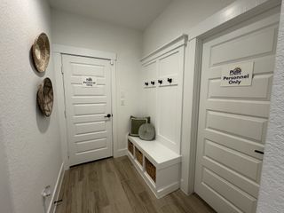 A welcoming entryway with neat white paneling, wooden floors, and stylish wicker decor.