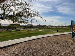 A scenic community park with lush greenery and playground in the Village at Sundance by Centex, Buckeye, AZ.