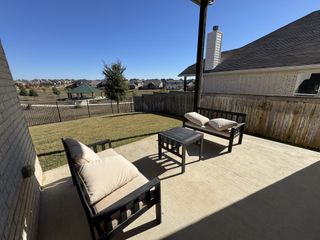 A cozy backyard patio with seating and open views, perfect for relaxing in the Sunfield community by CastleRock Communities (Buda, TX).