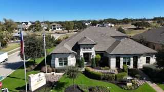 A spacious stone-brick home with manicured landscaping in Caliterra by Scott Felder Homes (Dripping Springs, TX).