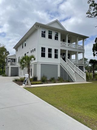 A charming coastal home with a wraparound porch in Enclave at Copahee Sound by Dream Finders Homes (Awendaw, SC).