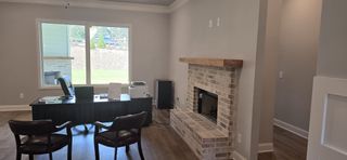 A cozy office with a brick fireplace, large window, and elegant wooden floors for a sophisticated workspace.