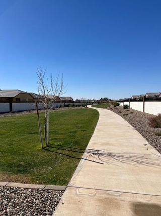 A scenic pathway winds through Anderson Farms: Premier by Lennar in Maricopa, AZ, with trees and well-kept lawns.