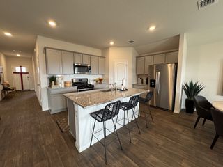 Model Home An open-concept kitchen and dining area with stainless steel appliances and a neutral color scheme.