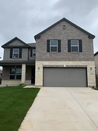 Street view A modern two-story home with stone accents and shutters in EastVillage - Heritage Collection by KB Home (Manor, TX).