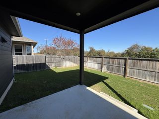 A cozy covered patio overlooks a private fenced backyard, perfect for outdoor relaxation.