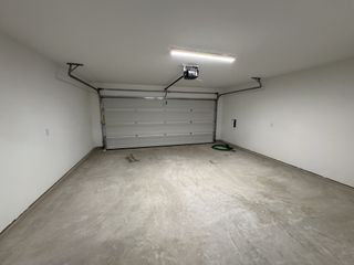 A spacious two-car garage with clean white walls and a sturdy overhead door, efficiently lit and neatly organized.