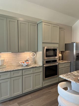 A modern kitchen with sleek gray cabinets, marble countertops, and stainless steel appliances.