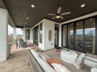 Model Home A spacious patio with cozy seating, ceiling fan, and dining area, perfect for outdoor relaxation and entertainment.