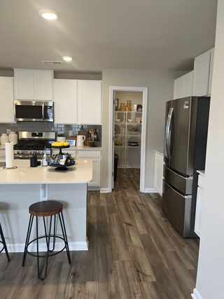 Model Home A modern kitchen with sleek white cabinets, stainless steel appliances, and a spacious island featuring bar stools.