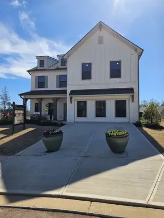 Model Home A sunny street view in Ponderosa Farms by Chafin Communities in Gainesville, GA, with a 25 MPH sign, showcasing new home construction and a clear blue sky.
