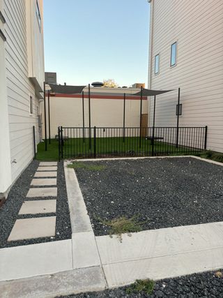 Street view A private, fenced backyard with a gravel patio and a shaded pergola, offering outdoor space at The Deco by Terramark Urban Homes in San Antonio, TX.